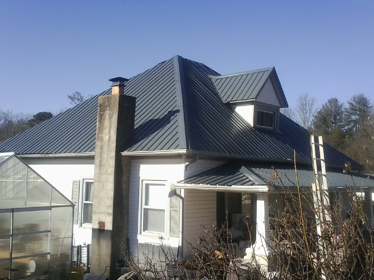Dark blue standing seam metal roof on a white farmhouse with dormer — Slate & Tile Roof Repair by Roofing Brothers in New Glarus