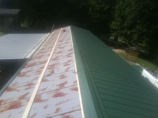 Old rusted panels beside newly installed green metal roofing — Wind Damage Roof Repair by Roofing Brothers in New Glarus