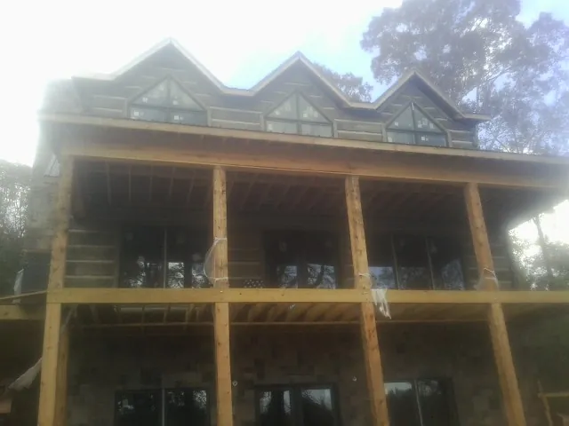 Dormers and porch framing on a large log home under construction — Roof Coating work by our crew in New Glarus