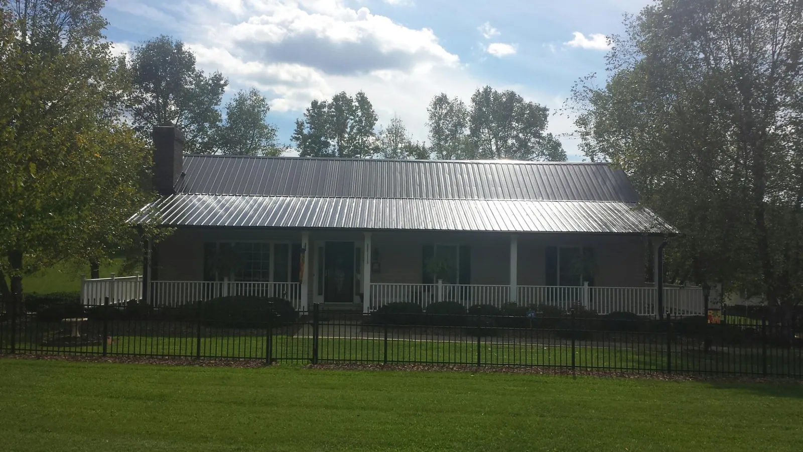 Gray metal roof on a brick ranch with a full width front porch — Gutter Guard Installation work by our crew in New Glarus