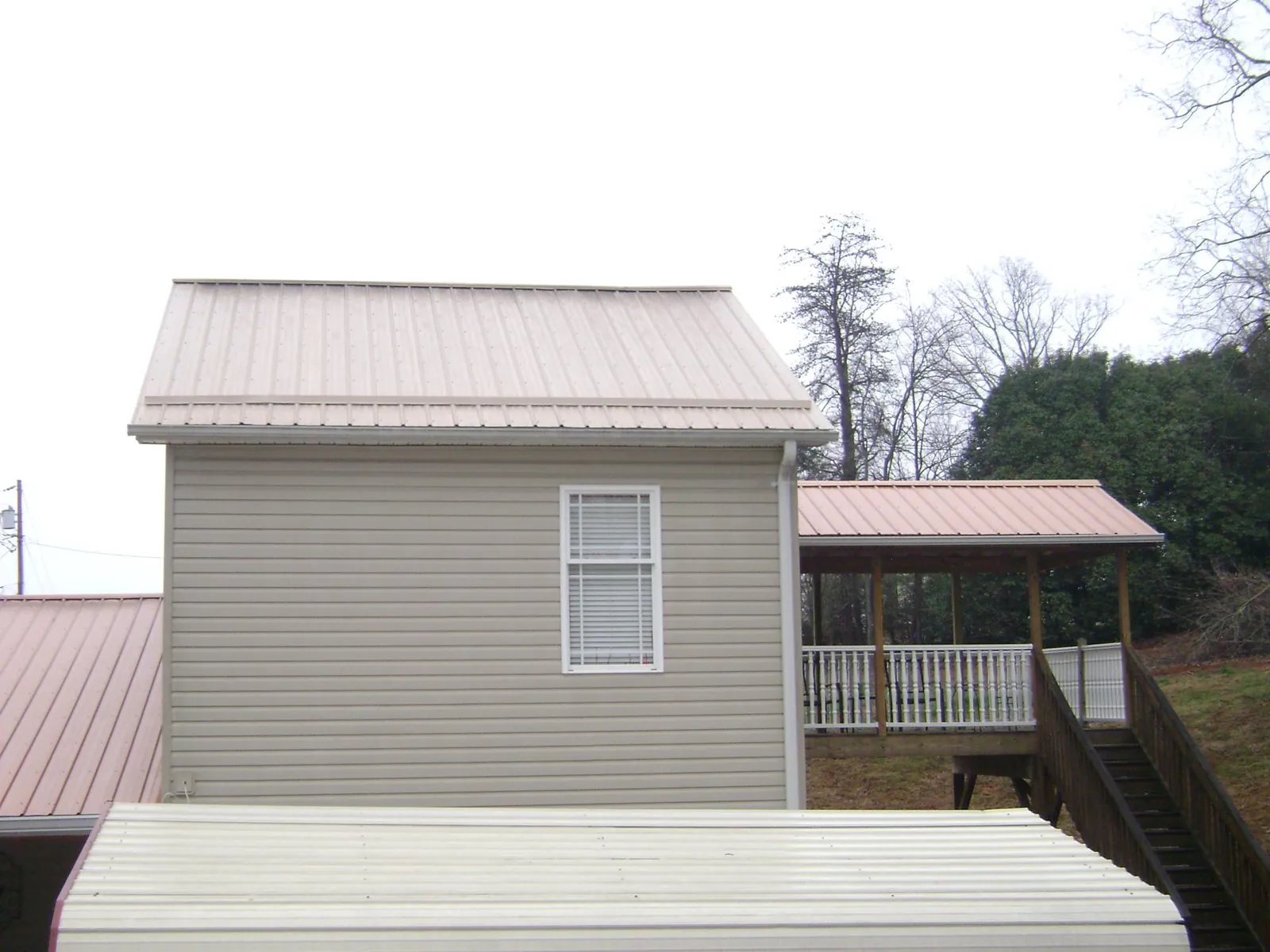 Tan metal roofs on a two story addition and attached porch, from a Roof Replacement job in New Glarus