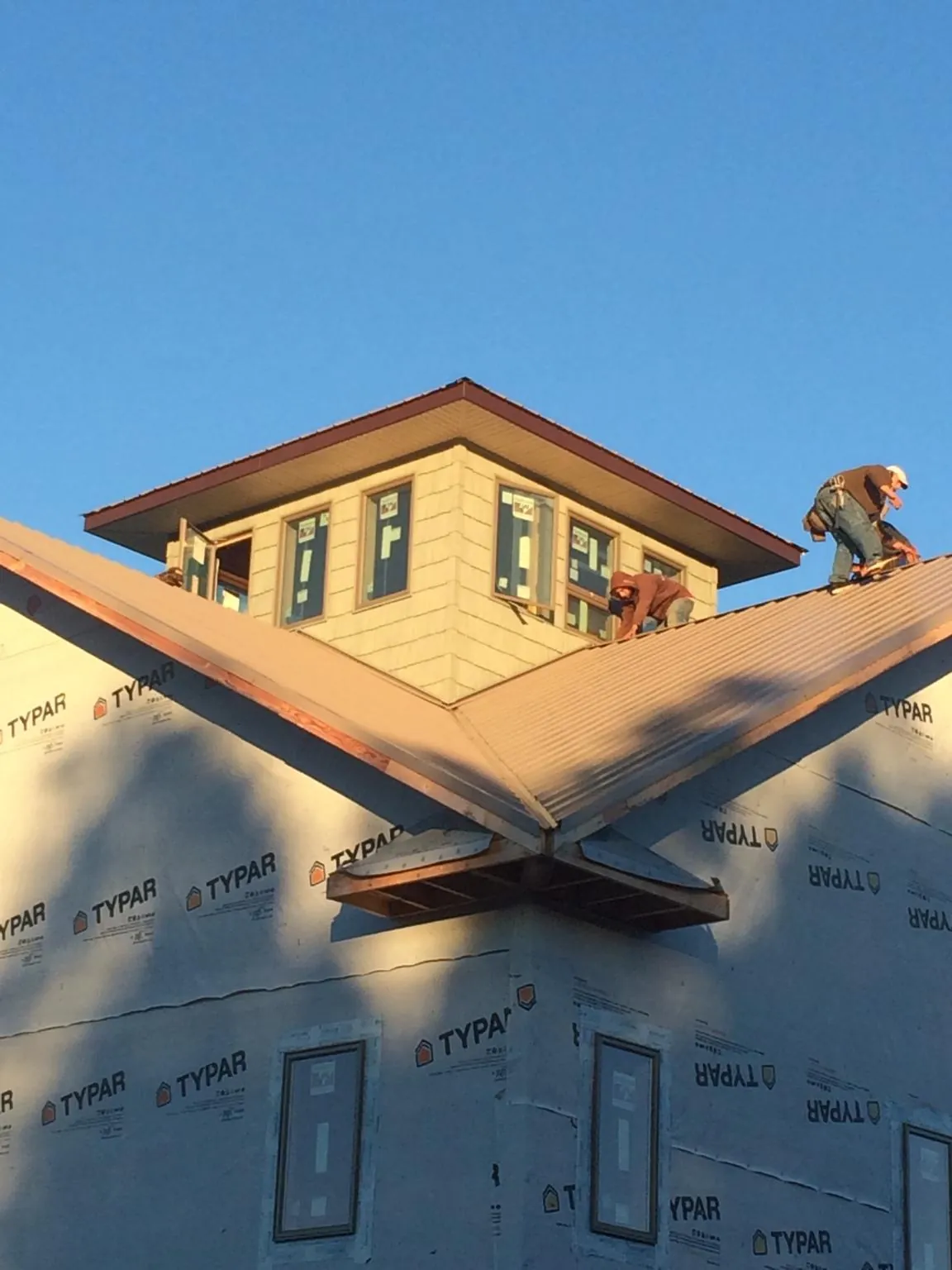 Roofers working around a rooftop cupola on a new metal roof at sunset — Roof Waterproofing in New Glarus by Roofing Brothers